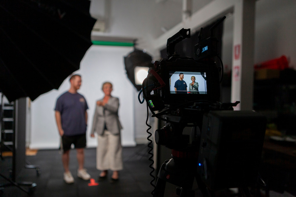 Behind the scenes of a photo shoot: camera focused on a man and woman posing under studio lighting, with their image captured on the camera's display screen.